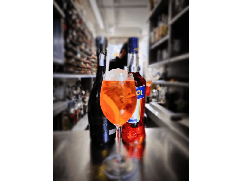 aperol spritz with prosecco and aperol bottle in the background