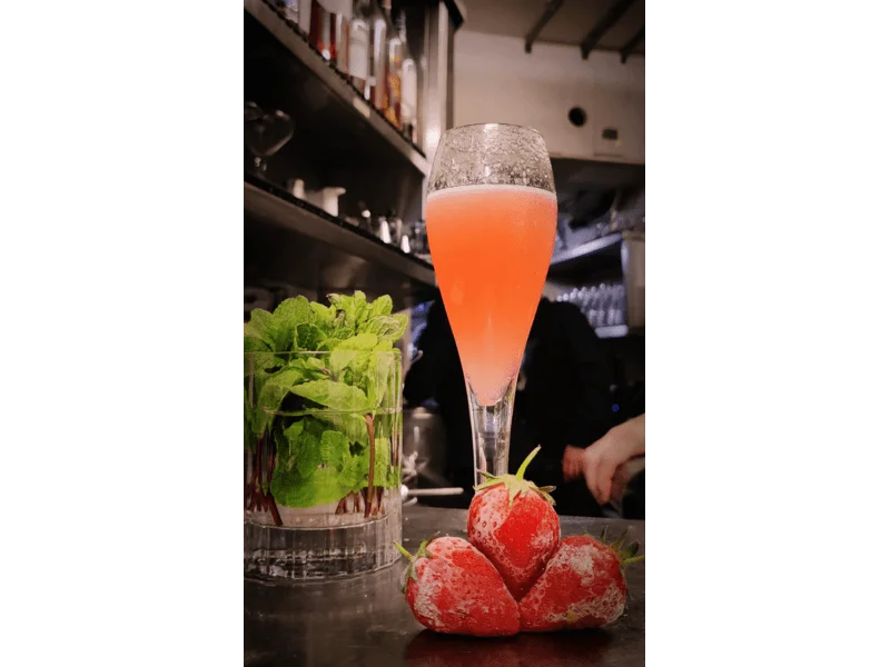 rossini cocktail with frozen strawberries in the foreground and a glass with mint on the right